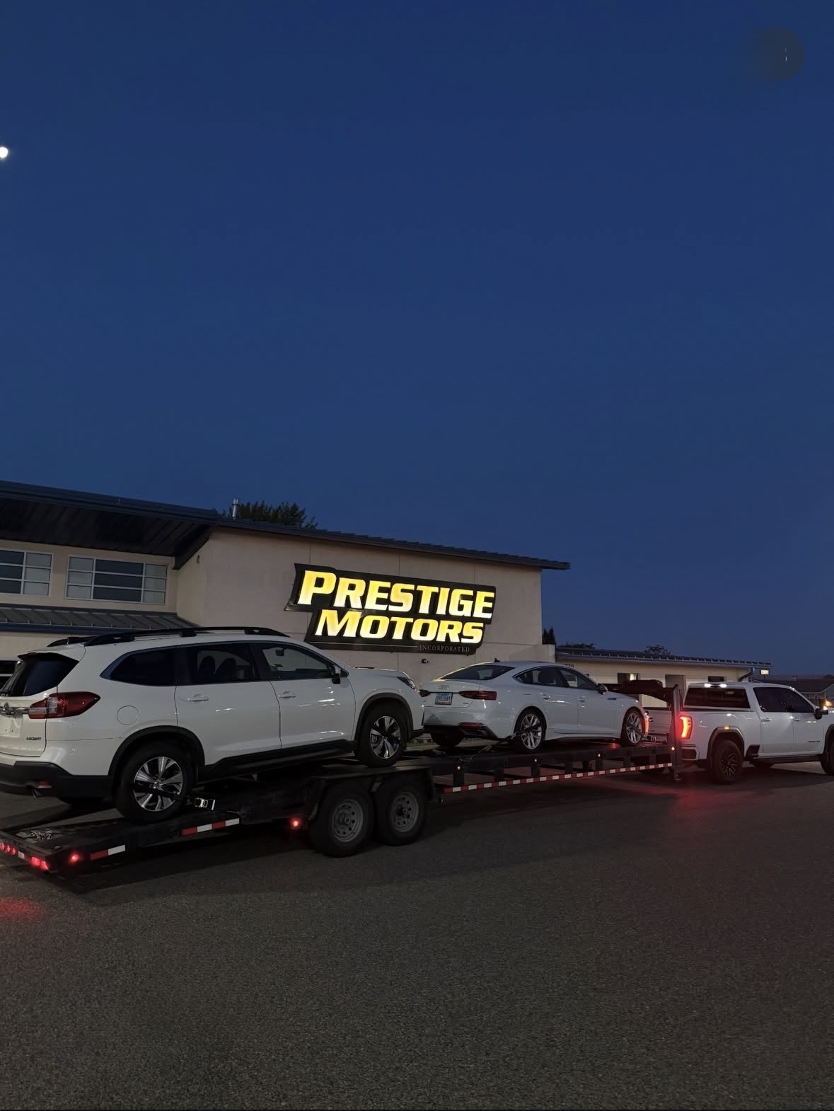 Royalty Auto Transport delivering vehicles to Prestige Motors at dusk