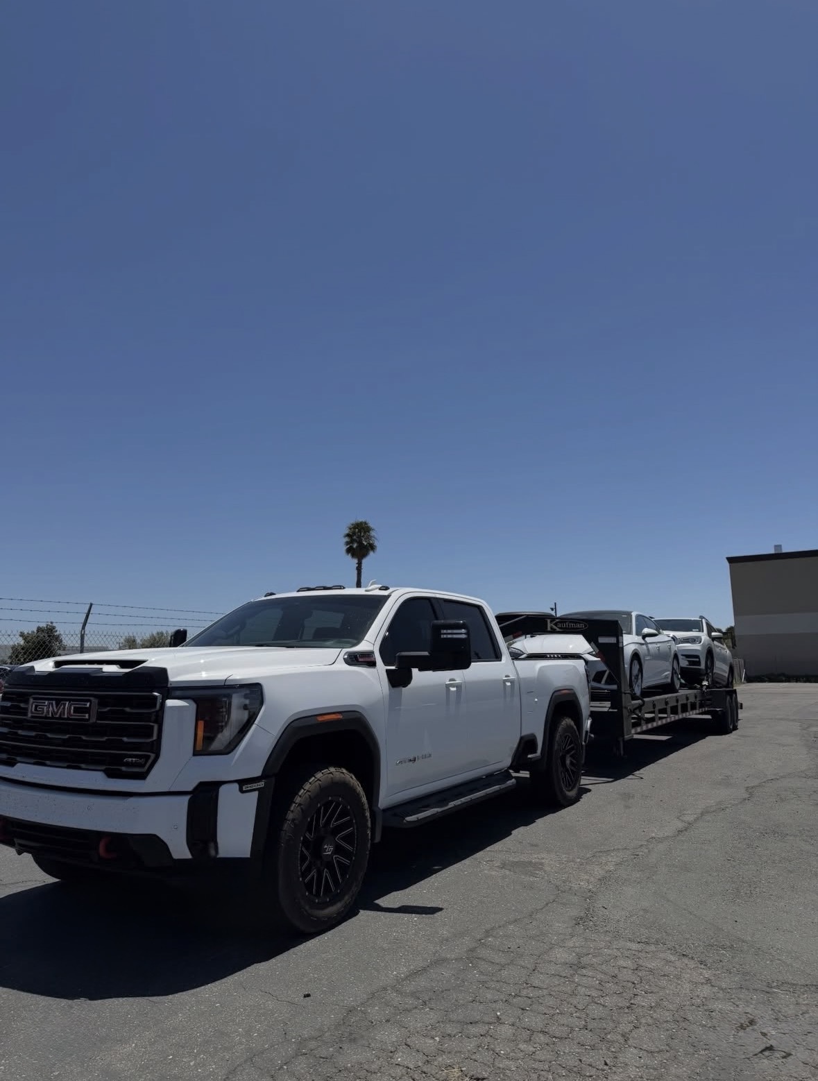 GMC pickup hauling a loaded Royalty Auto Transport trailer with multiple vehicles