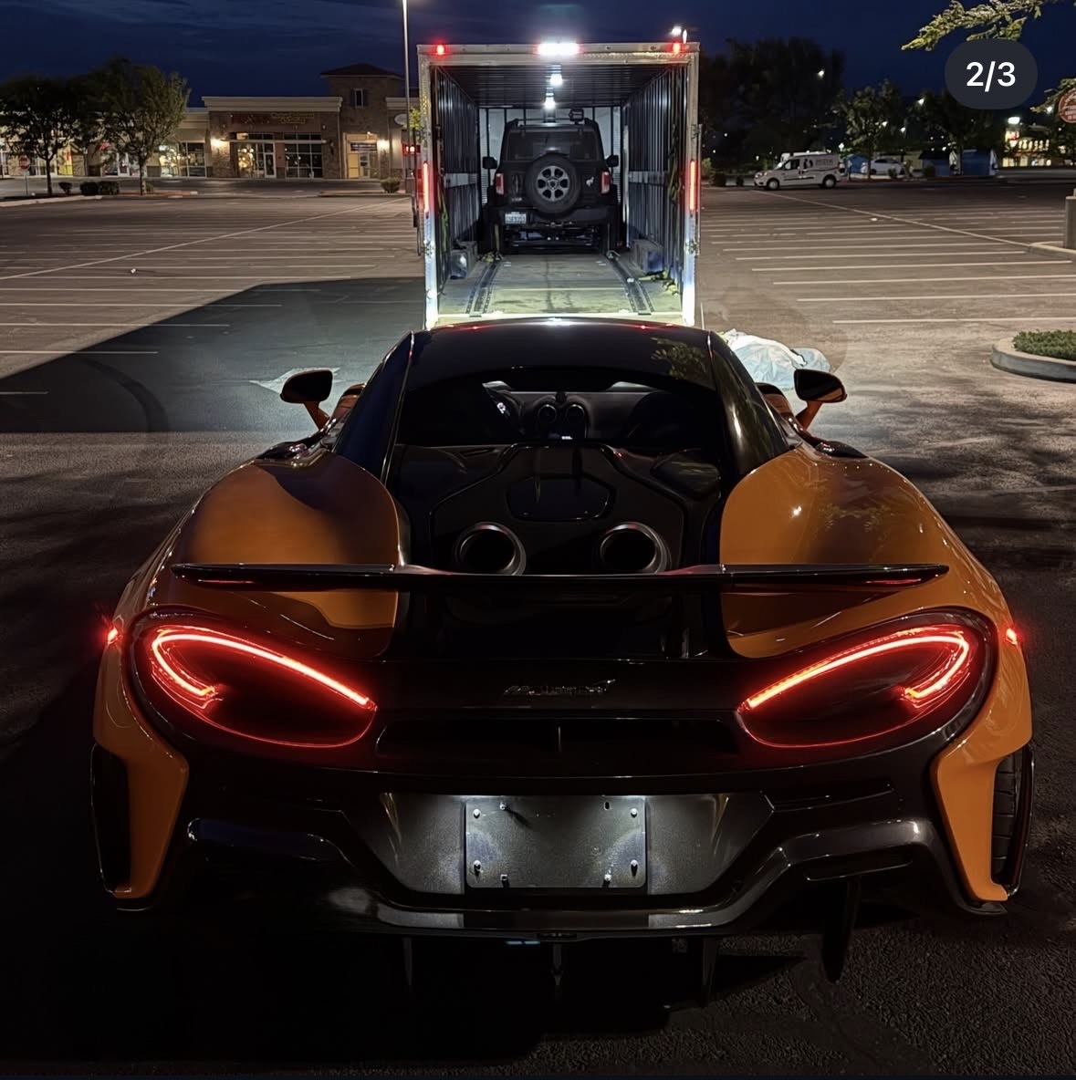 McLaren supercar being loaded into an enclosed Royalty Auto Transport trailer at night